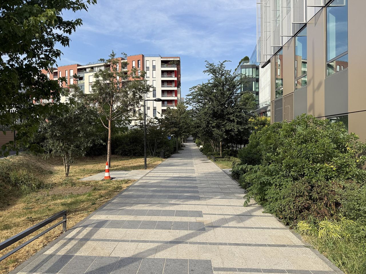 L'allée des Messageries à Bois-Colombes, un passage dallé bordé d'arbres et de massifs, entre des immeubles récents