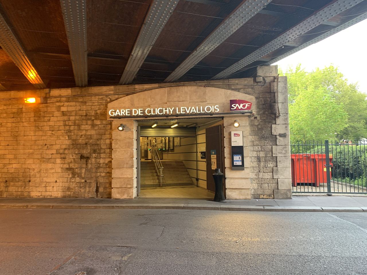 L'entrée de la gare de Clichy-Levallois sous le pont ferroviaire de la rue Paul-Vaillant-Couturier, éclairée à la tombée du jour.