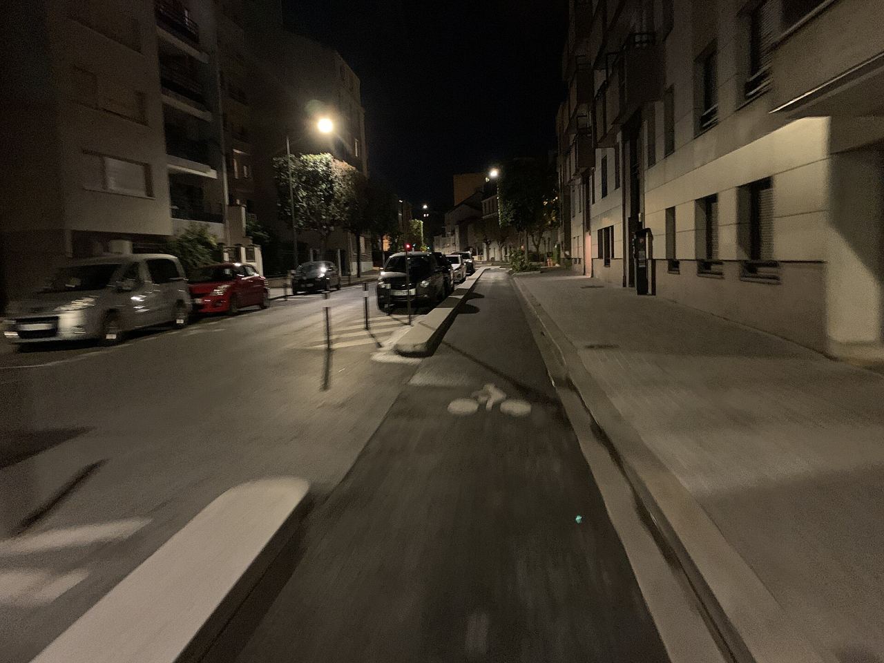 La piste cyclable de la rue Defrance à Vincennes, de nuit, séparée de la chaussée par une bordure, sous les lampadaires.